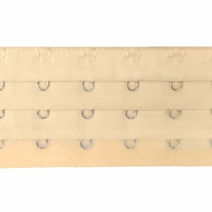 May include: Beige bra extender with three rows of metal hooks and eyes.