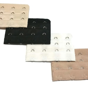 May include: Four bra strap extenders in different colors: beige, black, white, and beige. Each extender has multiple rows of hooks and eyes.