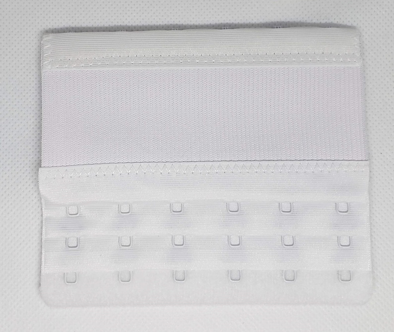 Peut inclure: Une extension de soutien-gorge blanche avec trois rang&eacute;es de fermetures &agrave; crochet et &oelig;illet. L'extension est faite d'un tissu doux et textur&eacute; et comporte une bande &eacute;lastique en haut. Cet accessoire de lingerie ajoute de la longueur &agrave; un soutien-gorge.