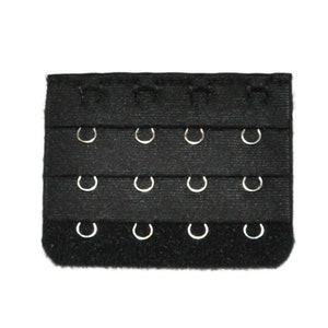 May include: Black bra extender with three rows of hooks and eyes. The extender has a hook and loop fastener on one end.