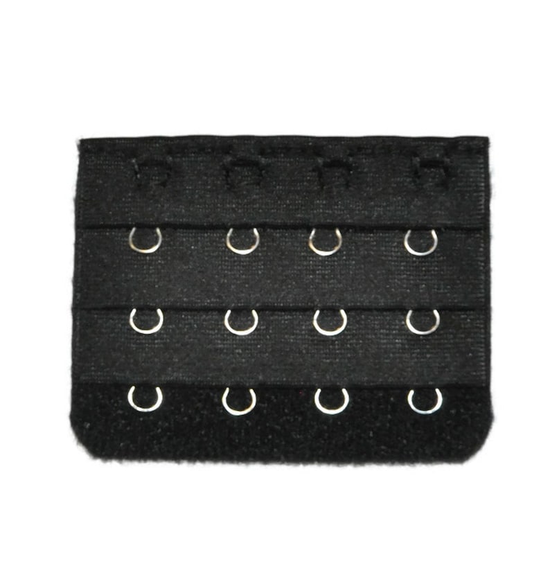 May include: Black bra extender with three rows of hooks and eyes. The extender has a hook and loop fastener on one end.