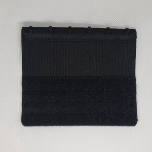Peut inclure: Une extension de soutien-gorge noire avec une fermeture &agrave; crochet et &oelig;illet. L'extension est de forme rectangulaire avec plusieurs ensembles de crochets et d'&oelig;illets pour un ajustement r&eacute;glable. Le tissu est lisse et tiss&eacute;.