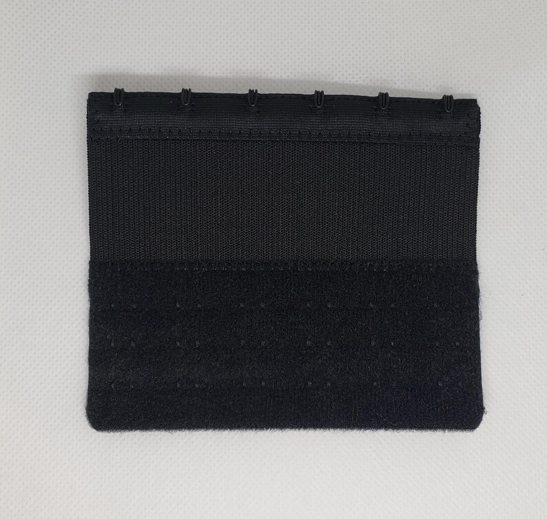 Peut inclure: Une extension de soutien-gorge noire avec une fermeture &agrave; crochet et &oelig;illet. L'extension est de forme rectangulaire avec plusieurs ensembles de crochets et d'&oelig;illets pour un ajustement r&eacute;glable. Le tissu est lisse et tiss&eacute;.