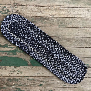 Peut inclure: Tapis tressé noir et blanc avec un motif géométrique. Le tapis est fait de tissu et a une forme arrondie.