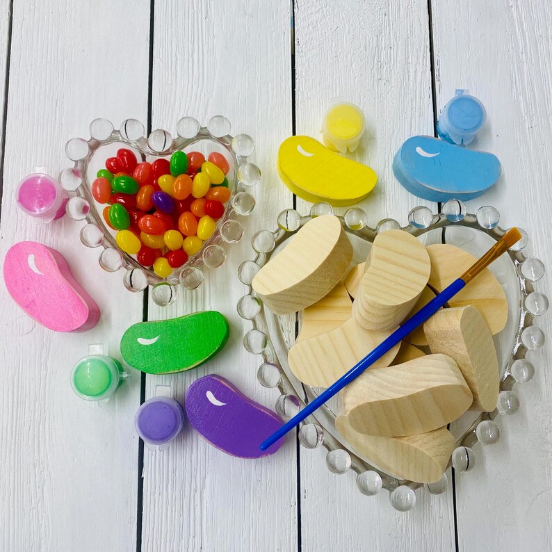 May include: A craft kit for painting wooden jelly bean shapes. The kit includes a variety of colors of paint, a paintbrush, and wooden jelly bean shapes. There are also jelly beans in a heart-shaped dish.