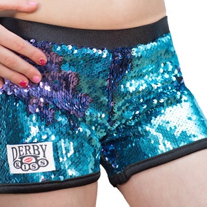 May include: Blue and purple sequined shorts with a black waistband and black trim. The shorts have a patch on the front that says "Derby Kiss" with a red lip logo.