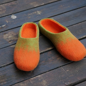 Könnte beinhalten: Ein Paar orangefarbene und grüne Filzpantoffeln. Die Pantoffeln sind aus Wolle und haben ein weiches, bequemes Tragegefühl.