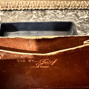 Puede incluir: Primer plano del interior de un bolso de cuero marr&oacute;n. El texto "BAG BY... Posef MADE IN ITALY" es visible. El bolso tiene un aspecto desgastado y vintage, con desgaste visible en el cuero.