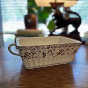 May include: White ceramic rectangular baking dish with brown floral design and two handles.