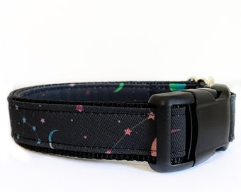 Puede incluir: Un collar de perro negro con un estampado celestial con lunas, estrellas y constelaciones. El collar tiene una hebilla de plástico negra.
