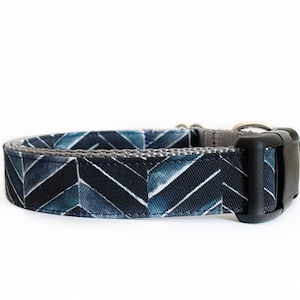 May include: A blue and gray dog collar with a chevron pattern. The collar has a black plastic buckle.