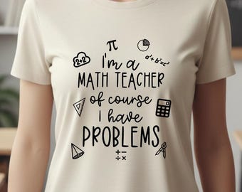 Może przedstawiać: Kremowy t-shirt z krótkim rękawem z czarnym napisem "I'm a MATH TEACHER of course I have PROBLEMS", otoczony różnymi symbolami matematycznymi i ikonami, w tym kalkulatorem, symbolem pi i kształtami geometrycznymi.