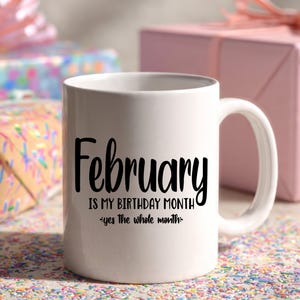 May include: White ceramic mug with the text "February is my birthday month - yes the whole month" in black script. The mug has a curved handle and is surrounded by wrapped gifts.