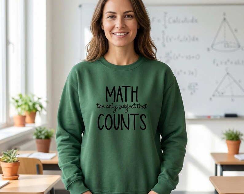 May include: A forest green long-sleeve crewneck sweatshirt featuring the black text "MATH the only subject that COUNTS" printed on the front. The garment has a ribbed neckline, cuffs, and hem, providing a standard fit for everyday wear.