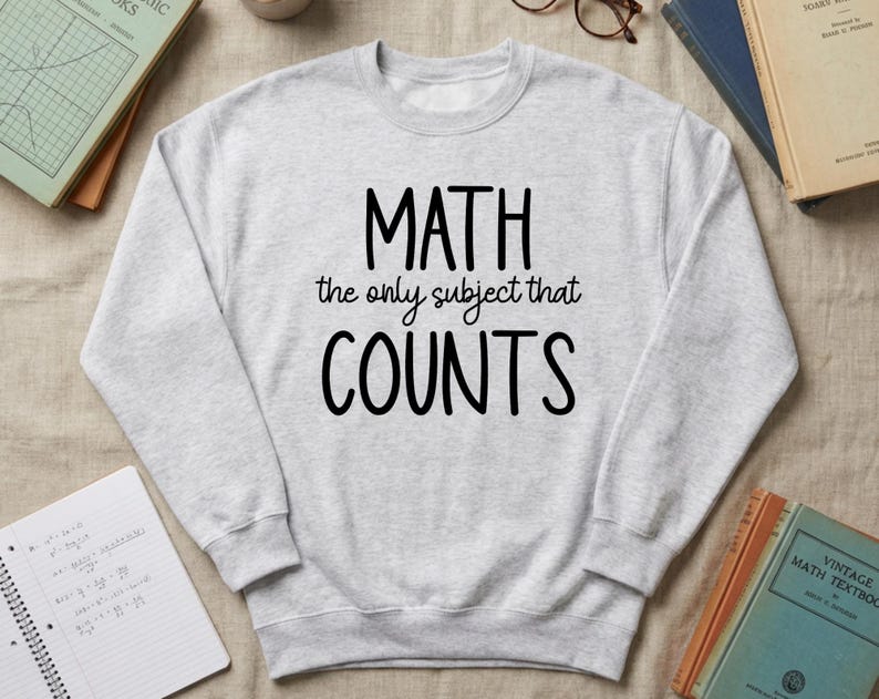 May include: A light gray sweatshirt with the text "MATH the only subject that COUNTS" in black. The sweatshirt is surrounded by books and a notebook with math equations.