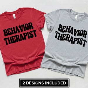 Pode incluir: Duas camisetas, uma vermelha e outra cinza, cada uma com a frase "BEHAVIOR THERAPIST" em letras pretas em negrito, estilo retrô. A imagem inclui um retângulo preto na parte inferior com o texto "2 DESIGNS INCLUDED".