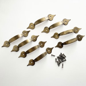 May include: Eight antique brass cabinet door pulls with a teardrop design and a set of screws.
