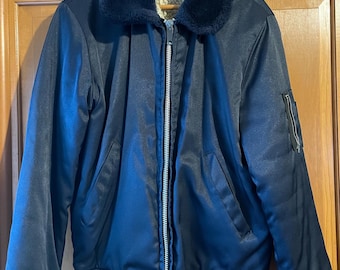 May include: A navy blue bomber jacket with a faux fur collar and a full-length zipper. The jacket has a ribbed hem and cuffs, and a zippered pocket on the left sleeve. The interior lining is a cream color.