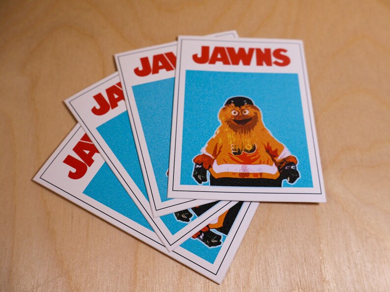 An array of 4 (four) stickers that look like the famous JAWS movie poster but feature a cartoon image of NHL Philadelphia Flyers mascot Gritty.