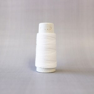 May include: A white spool of thread with the word "COATS" printed on the top.