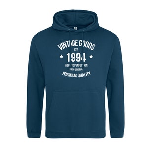 May include: A dark blue hooded sweatshirt with a white vintage goods logo. The logo says "Vintage Goods Est. 1994 Age to Perfection 100% Original Premium Quality".