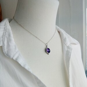 May include: A silver chain necklace with a pendant featuring a purple gemstone set in a silver bezel.