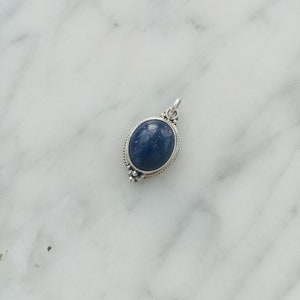 May include: A silver pendant with a dark blue oval gemstone set in a silver frame.