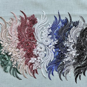 Könnte beinhalten: Eine Sammlung von Perlen-Spitzenapplikationen in verschiedenen Farben, darunter Grün, Rosa, Rot, Weiß, Blau und Schwarz. Die Applikationen zeigen komplizierte Blumen- und Blattdesigns.
