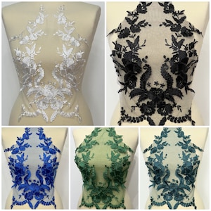 Può includere: Quattro applicazioni in pizzo di diversi colori: bianco, nero, blu e verde. Ogni applicazione presenta un motivo floreale con dettagli intricati.