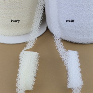 May include: Two spools of white lace trim, one ivory and one white. The lace trim has a scalloped edge with a delicate floral pattern.
