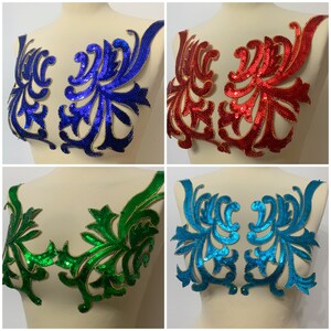 Op de afbeelding: Vier paillettenstoffapplicaties in verschillende kleuren: blauw, rood, groen en turquoise. Elke applicatie heeft een bloemmotief met gouden accenten.