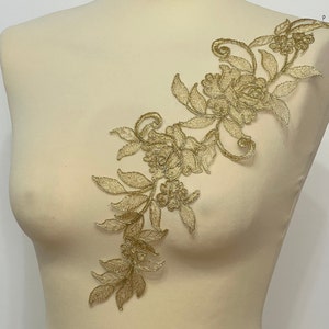 May include: Gold floral lace applique with delicate leaves and flowers. This intricate design is perfect for adding a touch of elegance to clothing, accessories, or home decor projects.