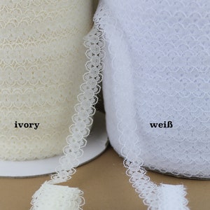 May include: Two spools of white lace trim, one ivory and one white. The lace has a delicate scalloped edge.