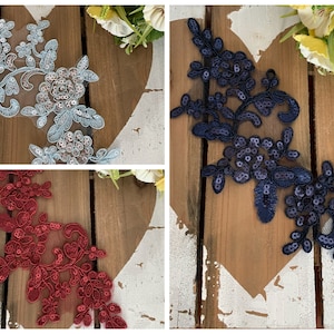 Può includere: Tre applicazioni in pizzo floreale con paillettes. Le applicazioni sono in azzurro, blu navy e rosso.