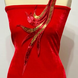 May include: Red velvet fabric with a gold and red sequined design. The design is a stylised flame shape.