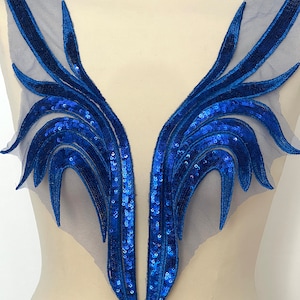 Könnte beinhalten: Eine blaue Pailletten- und Mesh-Applikation mit V-Ausschnitt. Die Applikation zeigt ein Blumenmuster mit einem geschichteten Look.