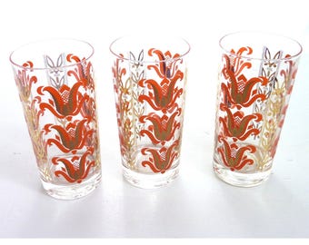Juego de 3 vasos de zumo vintage MCM con diseño floral retro en naranja y dorado.