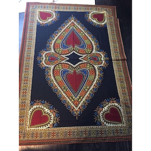 May include: A large, rectangular textile with a dark blue background. The design features a central heart shape and four smaller heart shapes, all in red. The hearts are surrounded by intricate patterns in yellow, blue, green, and orange. A decorative border frames the design.