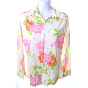 May include: White button-down shirt with a floral pattern. The long-sleeved shirt features large pink and orange flowers with green leaves. The shirt is displayed on a white mannequin.