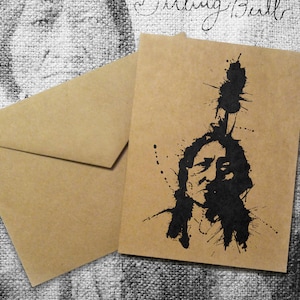 May include: A kraft paper greeting card and envelope set. The card features a black ink illustration of Sitting Bull with a splatter effect. The words "Sitting Bull" are handwritten in cursive.