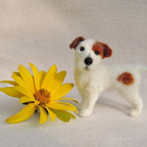 May include: A white and brown needle felted Jack Russell terrier dog figurine with a yellow flower.