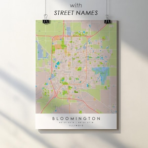 May include: A map of Bloomington, Illinois, with street names, is displayed on a poster. The map features a detailed layout of the city, with roads, parks, and buildings in various colors. The poster is held by black clips.