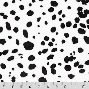 May include: White fabric with a black dalmatian spot pattern. The spots vary in size and shape, creating a playful and recognizable design. A ruler is at the bottom of the image, with markings in inches.