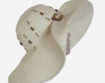 Cappello da spiaggia ecologico in lino color latte con tesa larga e perline di legno.