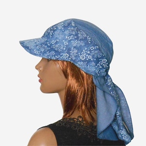 Pode incluir: Um lenço azul com um padrão floral branco está amarrado em volta da cabeça de uma pessoa e amarrado na parte de trás do pescoço. O lenço tem uma aba na frente e é usado como um chapéu.