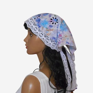May include: A floral patterned headscarf with a white lace trim. The scarf features a watercolor design with blue, purple, and pink hues. The lace trim adds a delicate touch to the head covering.