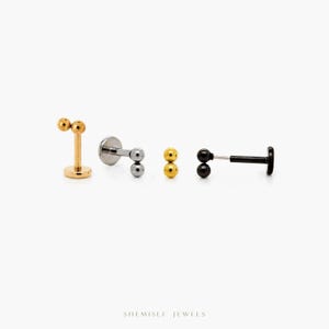 May include: A selection of labret earrings in gold, silver, and black. Each earring has a small ball on the front and back. The earrings are presented against a white backdrop. The brand name "SHEMISLI JEWELS" is at the bottom.