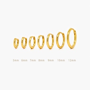 May include: A selection of gold-coloured hoop earrings, varying in size from 5mm to 12mm. The earrings are displayed in a line, highlighting their different diameters. The background is plain white.