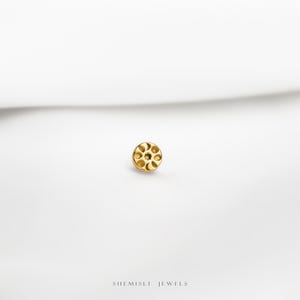 a close up of a gold plated object on a white surface