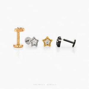 Peut inclure: Quatre boucles d'oreilles en forme d'étoile en or, argent et noir. La boucle d'oreille dorée a une tige et un dessus en forme d'étoile. La boucle d'oreille argentée a un dessus en forme d'étoile avec une gemme.